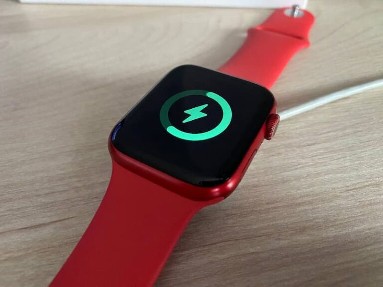 Apple Watch z czerwonym paskiem podczas ładowania – zielony symbol pioruna na ekranie